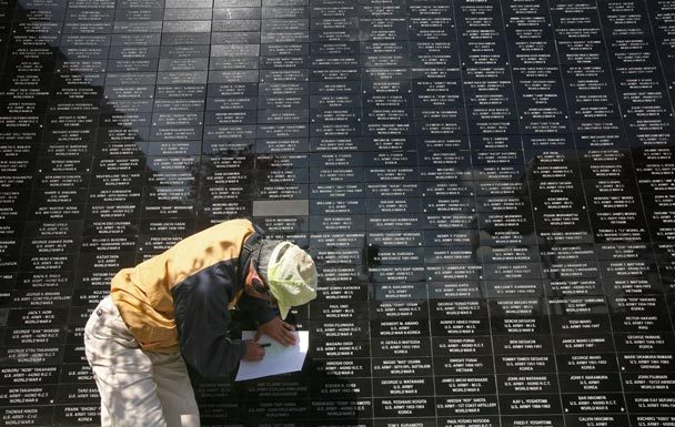 Korean War veteran Mas Koba traces over the brick bearing his name and service record before the dedication of the NVC Foundation's new Japanese American memorial wall in Seattle's Chinatown International District on Sunday. 